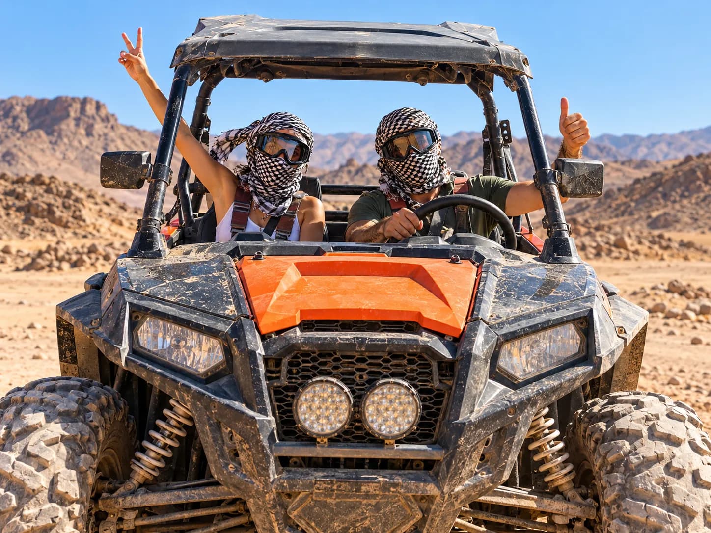 Couple next to a red buggy watching the winter sunset over the desert mountains near Hurghada
